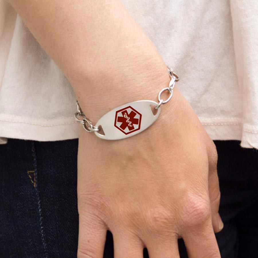 Woman wearing the silver-tone Stainless Red Oval Medical ID Tag with a red caduceus in the center on an LH bracelet