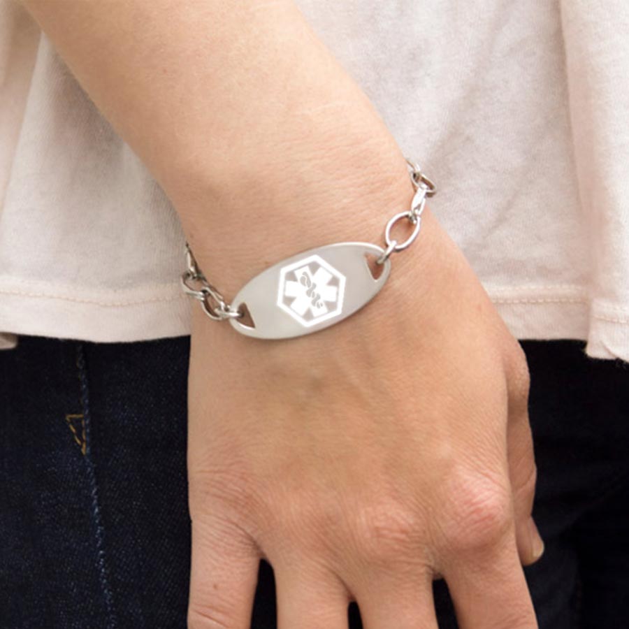 Woman wearing the silver-tone Stainless White Oval Medical ID Tag with white caduceus symbol in the center on an LH bracelet