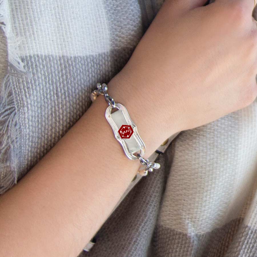 Woman wearing silver tone stainless steel La Petite Medical ID tag with red caduceus on a Lauren’s Hope med ID bracelet