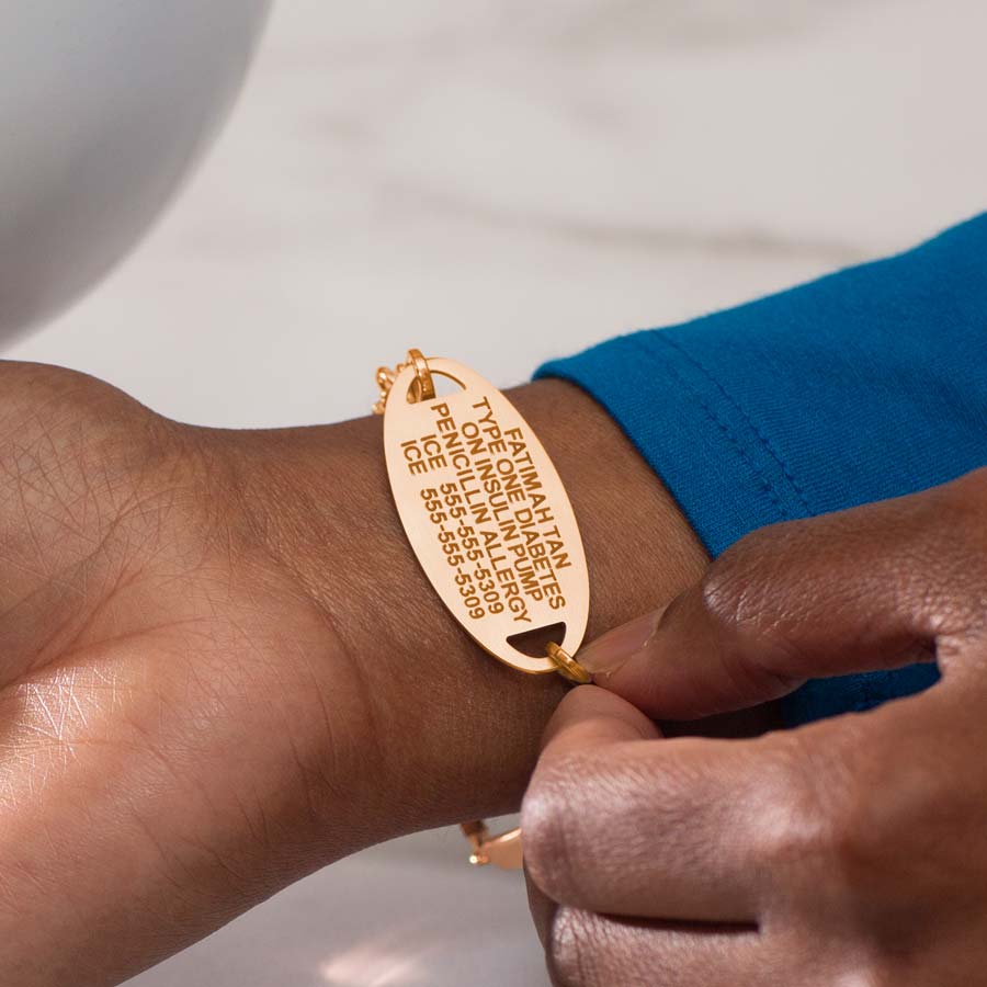 Woman in blue wearing rose gold tone med ID tag showing premium laser engraving on the inside of the tag.