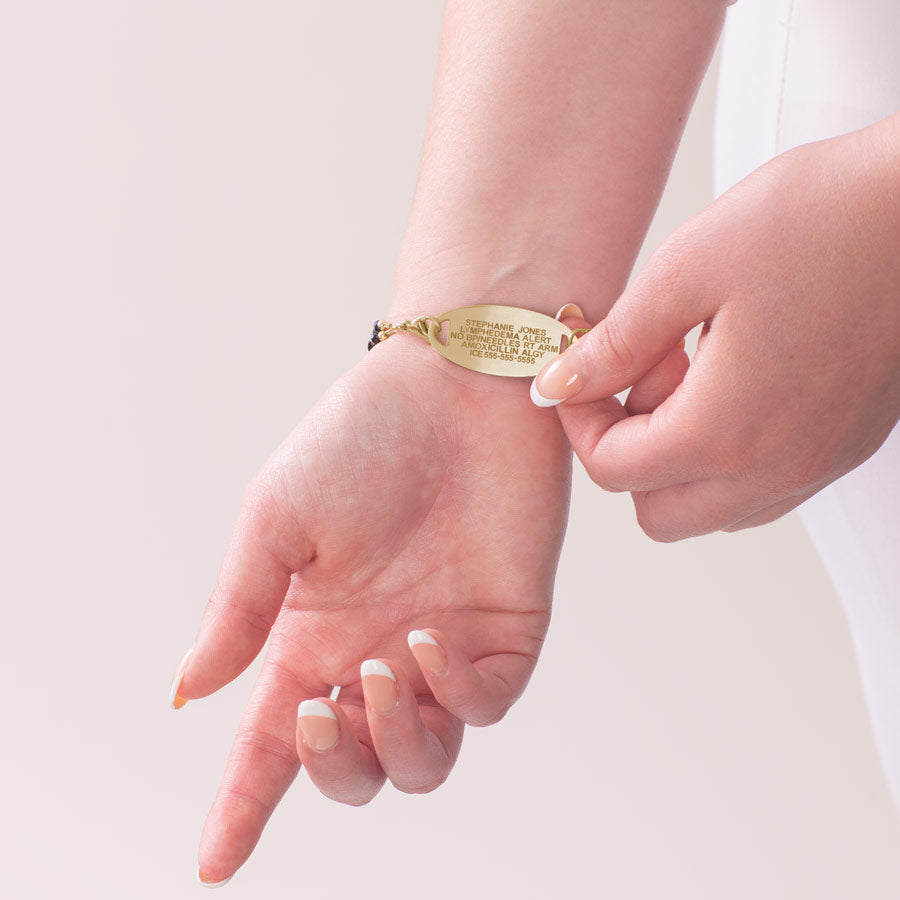 Woman showing custom laser engraved medical ID tag in gold