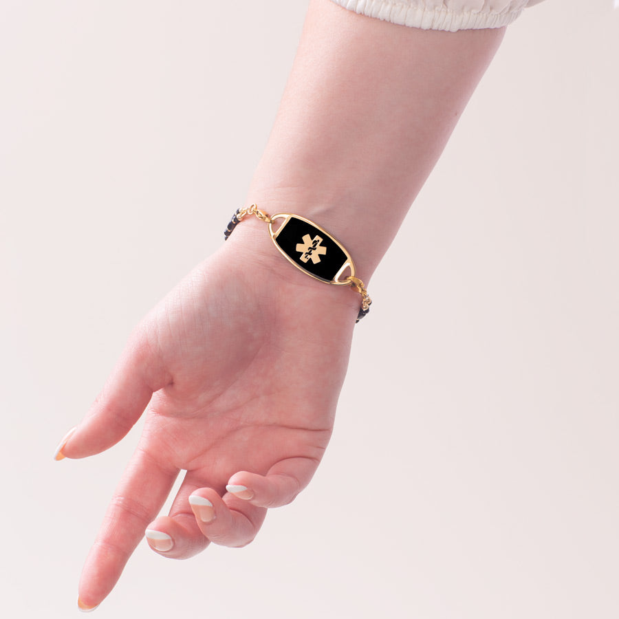 Woman wearing gold medical ID bracelet with black enamel medical alert tag