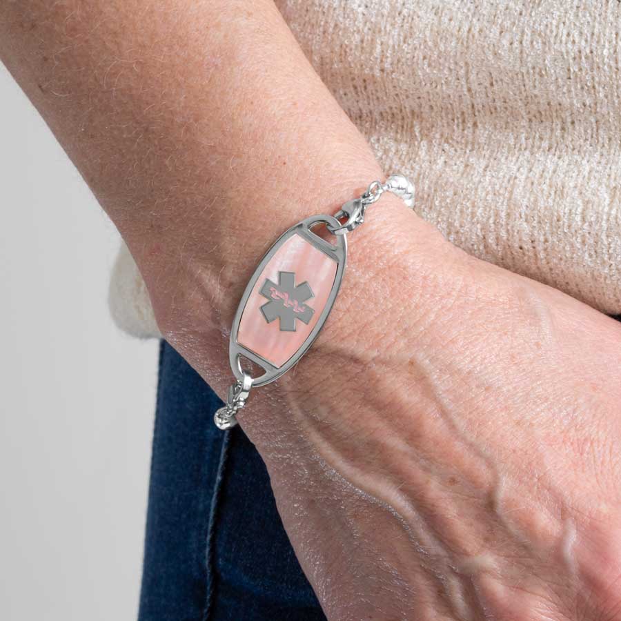 Woman wearing pink mother of pearl and silver medical ID alert tag with silver medical ID bracelet