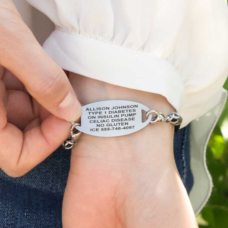 Woman wearing Black Macrame Medical ID Bracelet with oval stainless medical ID tag. Shows engraving on the back of the ID tag