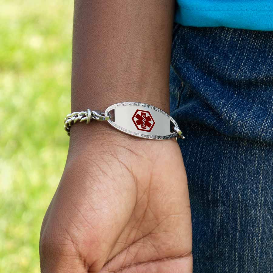 Boy showing medical alert tag with red medical symbol