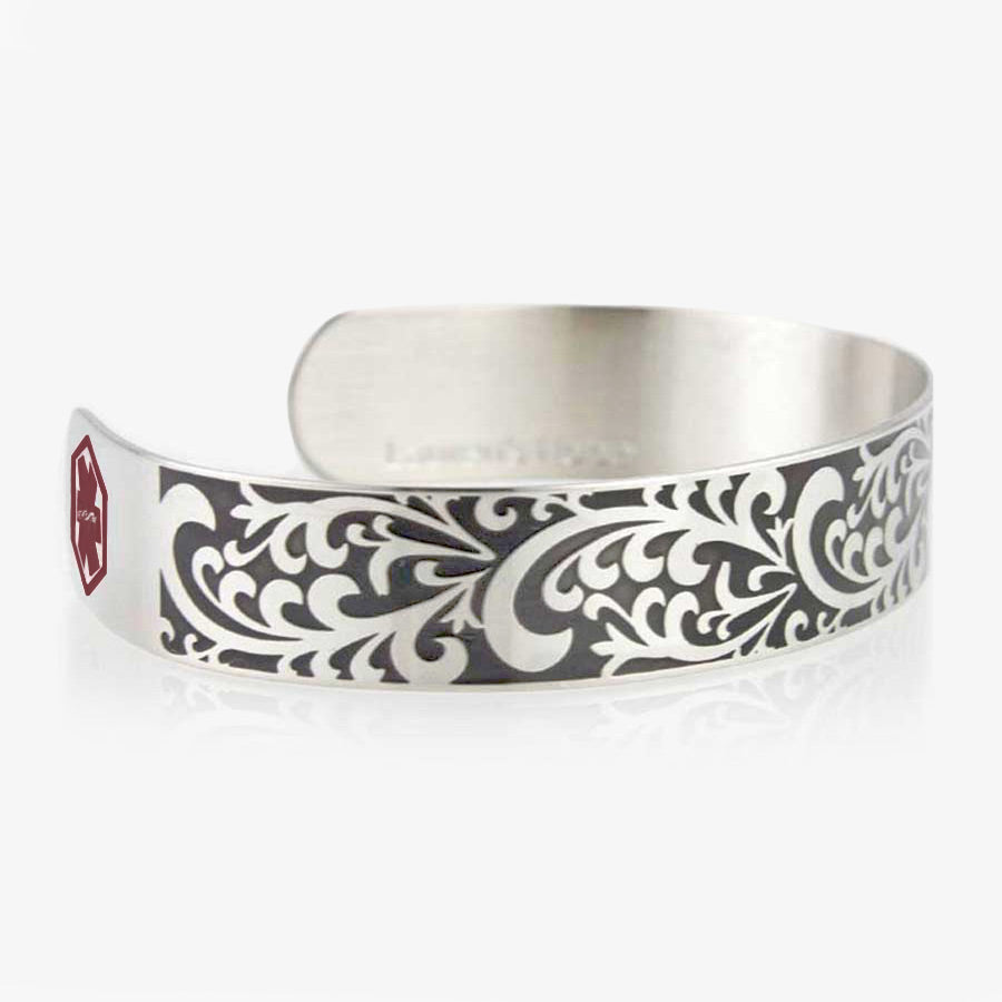 Side of Filigree Medical Alert Cuff. 1/2&quot; wide silver tone stainless cuff. Intricately scrolled design. Red caduceus each end