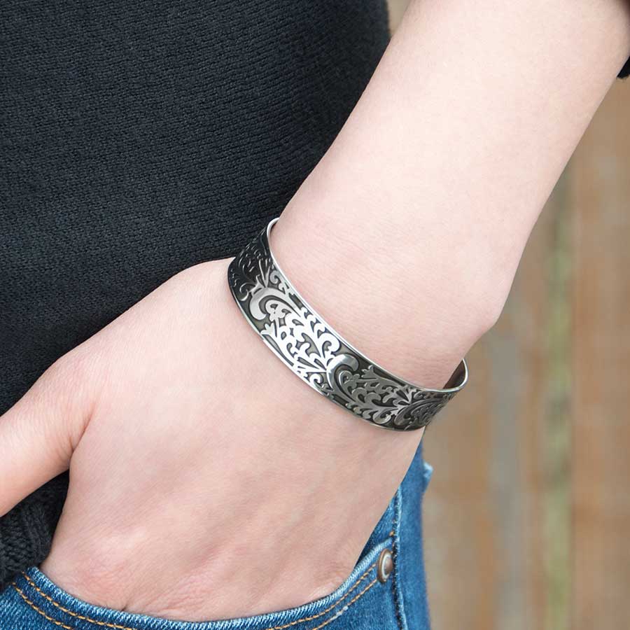 Woman wearing Filigree Medical Alert Cuff. Silver tone stainless cuff, intricately scrolled design with dark patina inlay