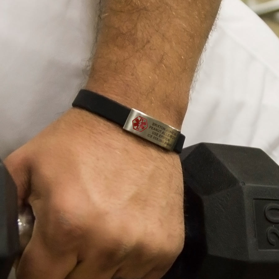 Boy wearing Medical ID Bracelet. Slim black silicone circle band with stainless plaque with red caduceus. Engraving on front