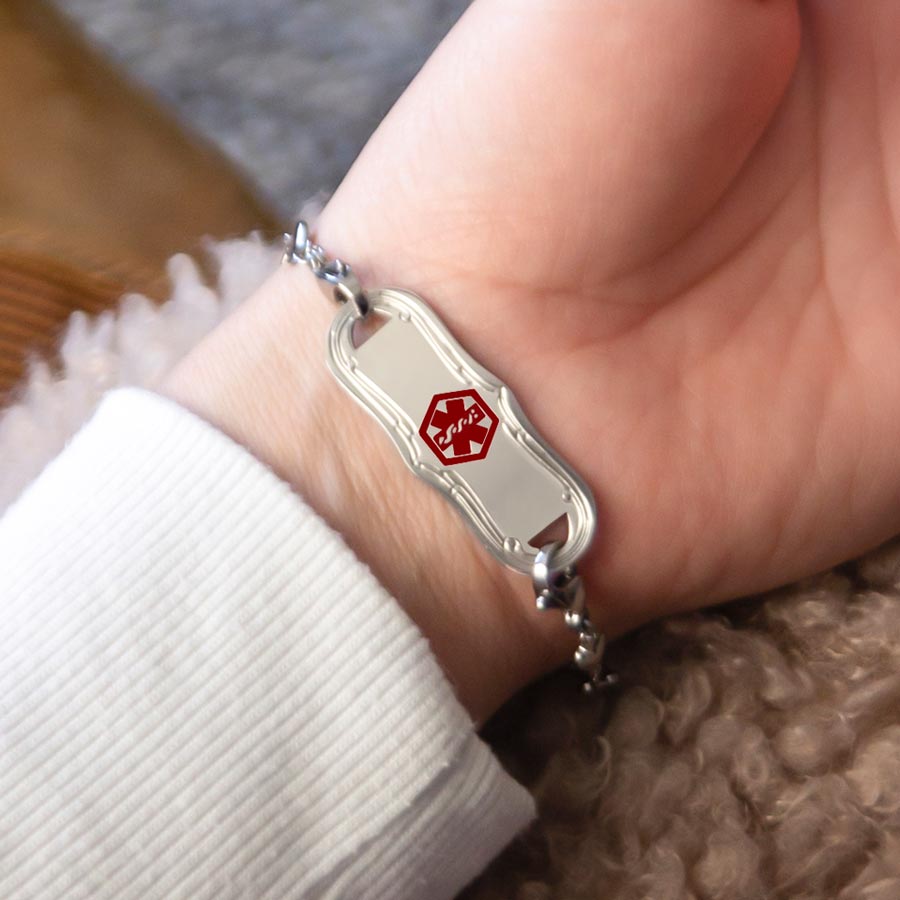 Woman showing silver medical ID tag with decorative edge and red medical caduceus symbol