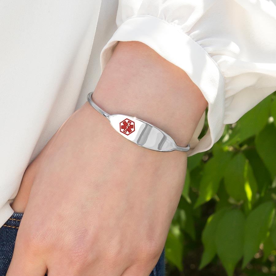 Woman wearing Micro Cuff Medical ID Bracelet. Slip-on silver-tone stainless bracelet with red caduceus