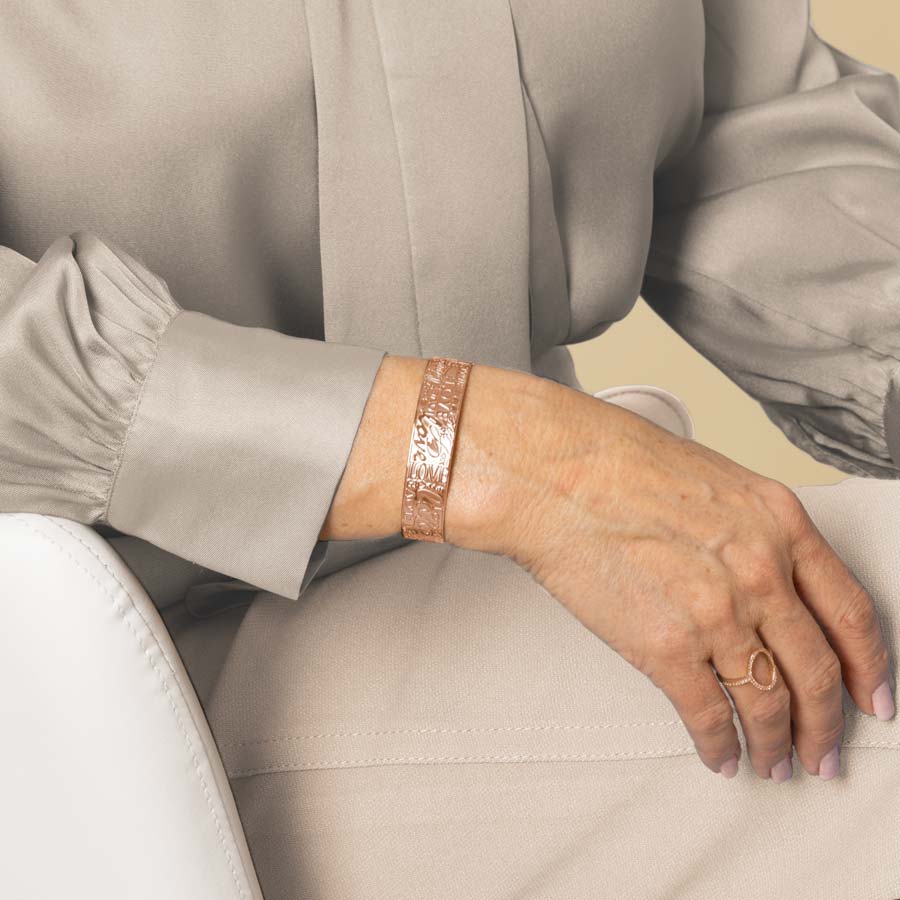 Woman wearing rose gold medical ID cuff with embossed hearts and X&#39;s and O&#39;s