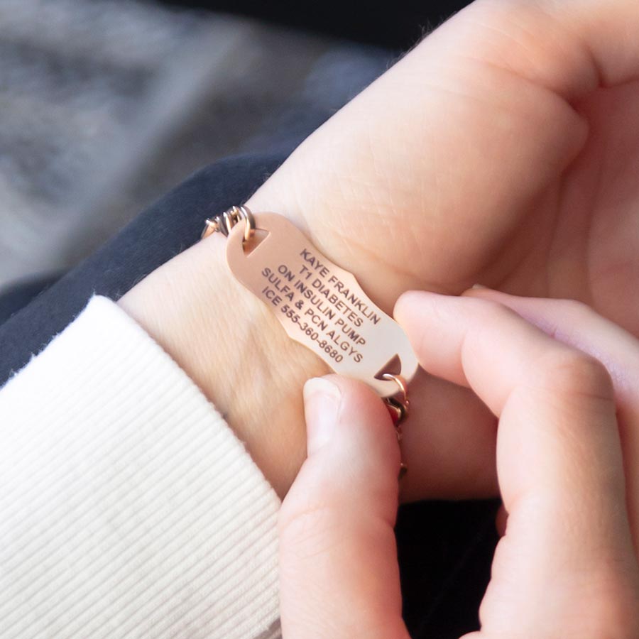 Woman showing custom laser engraved rose gold medical alert tag