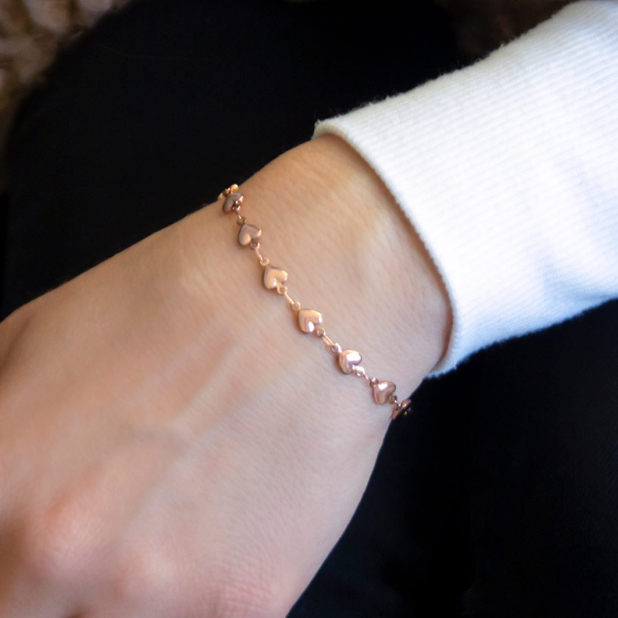 Woman wearing rose gold chain medical ID bracelet with tiny heart links