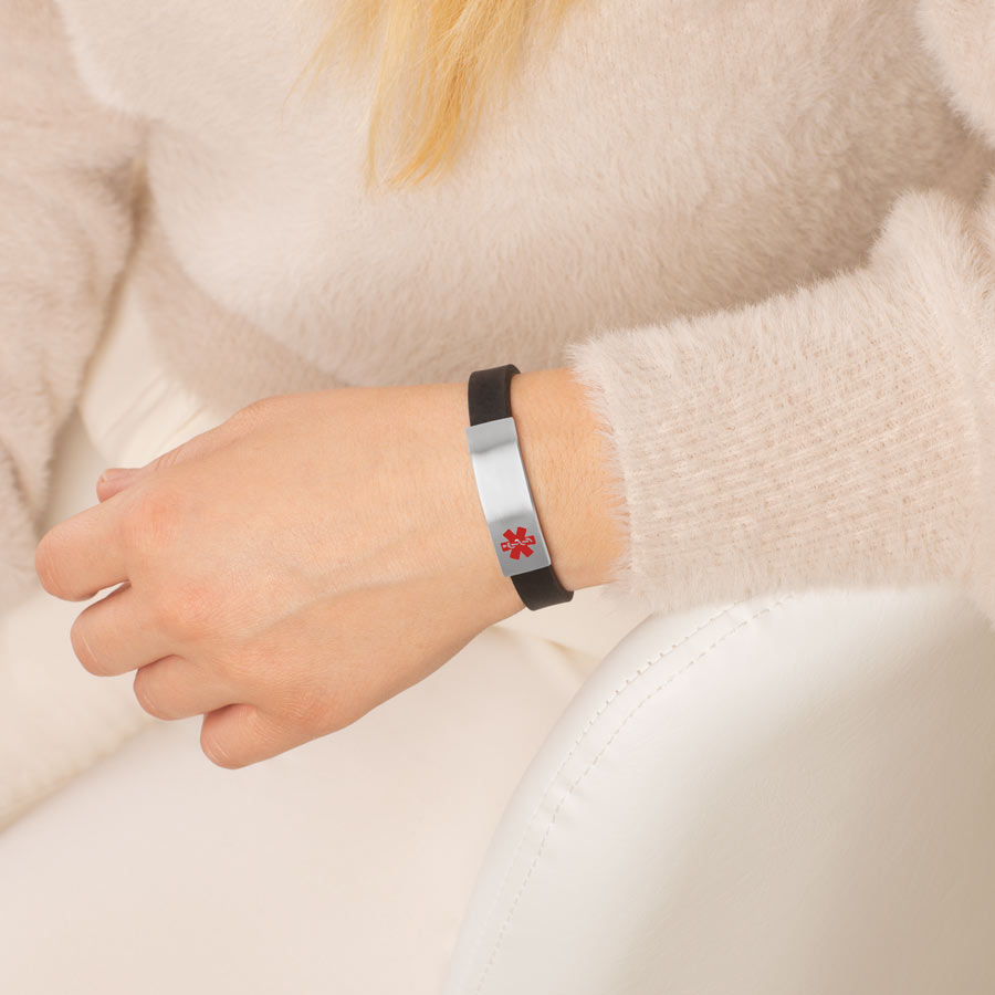 Woman wearing black silicone medical ID bracelet with stainless steel medical alert tag.