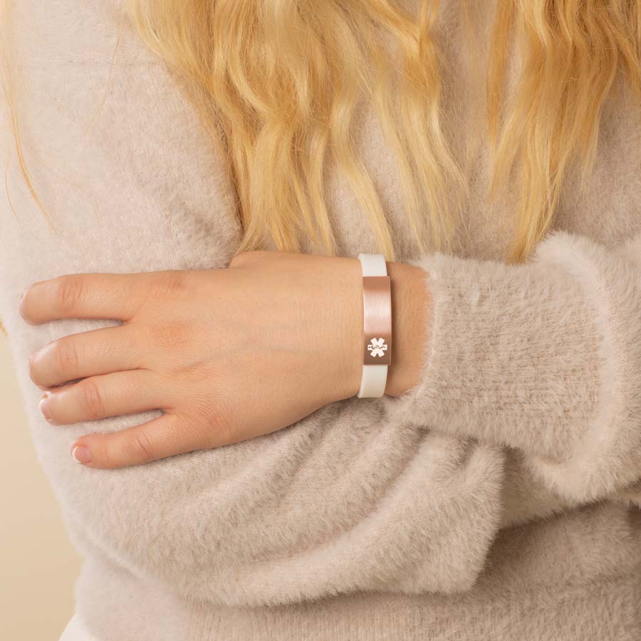 Woman wearing white silicone medical ID bracelet with rose gold tone stainless steel medical alert tag.