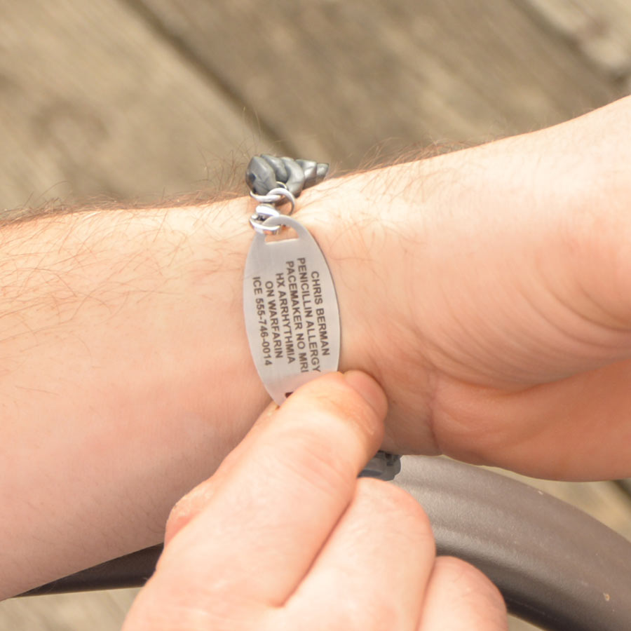 Man showing custom premium laser engraving on silver medical ID tag