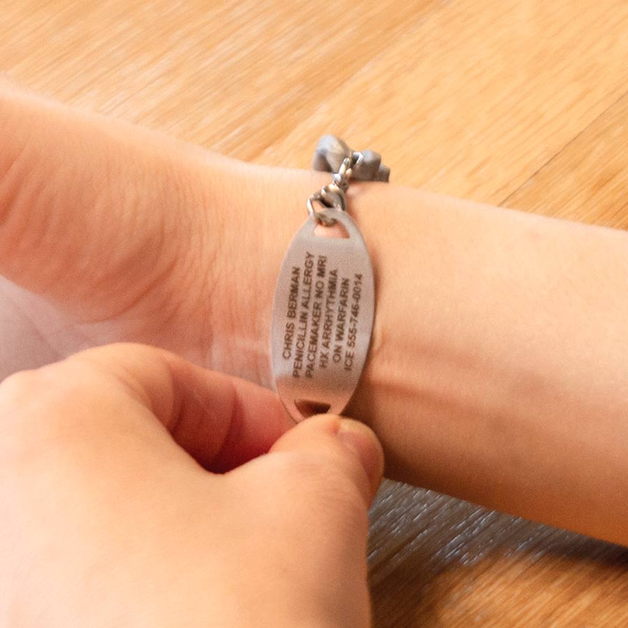 Woman showing custom premium laser engraving on silver medical ID tag