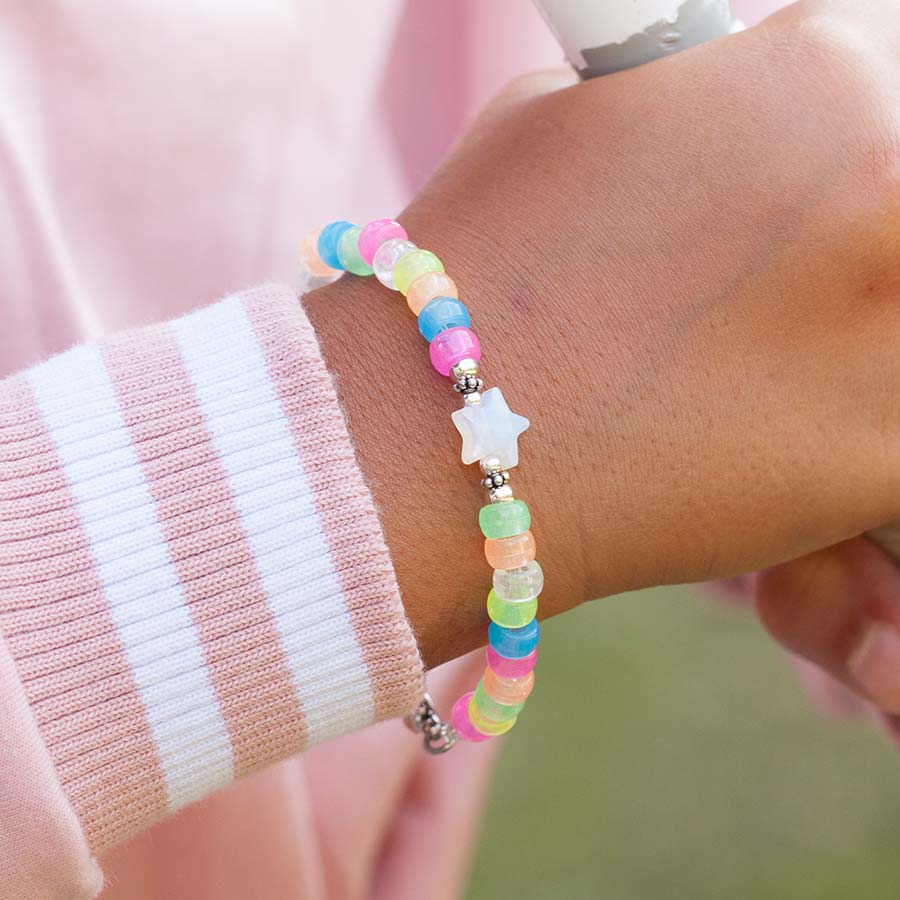 Young girl playing soft ball wearing colorful beaded medical ID bracelet with rainbow beads.