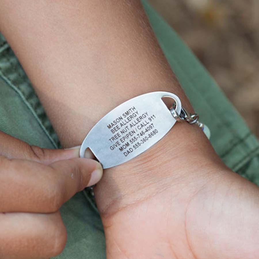 Little boy showing custom laser engraving on back of medical ID tag.