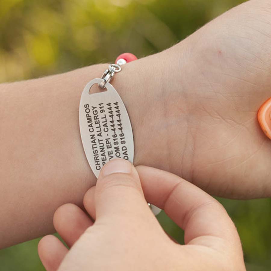 Girl flipping over medical ID tag to show the medical details custom laser engraved on back of tag.