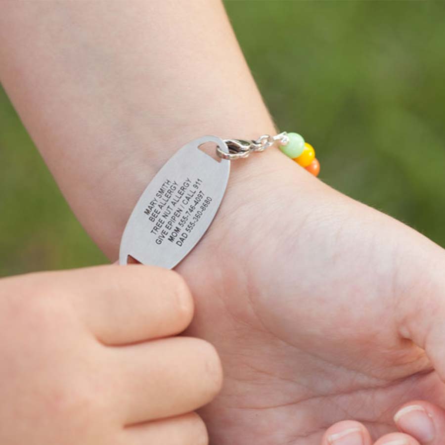 Girl flipping over medical ID tag to show the medical details custom laser engraved on back of tag.