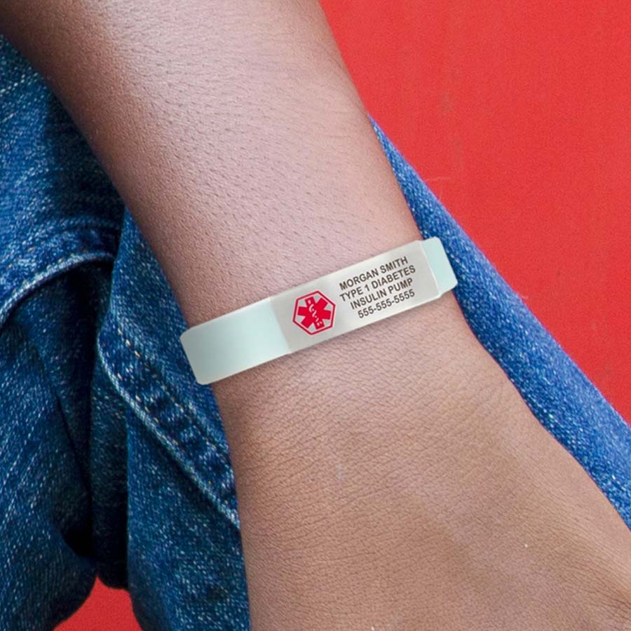 Boy in blue jeans with his arm propped up on his knee, wearing soft blue glow-in-the-dark silicone bracelet.