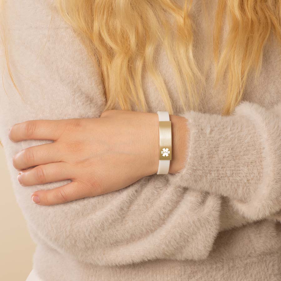 Woman wearing white silicone medical ID alert bracelet with brushed gold medical ID tag