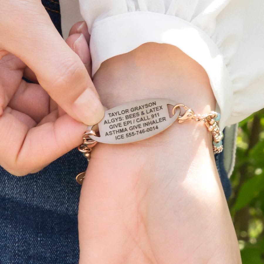 Woman showing custom laser engraved rose gold medical alert tag