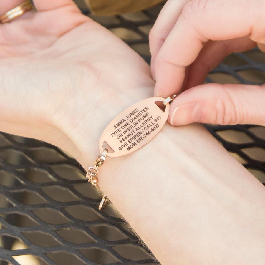 Woman showing custom laser engraved rose gold medical alert tag