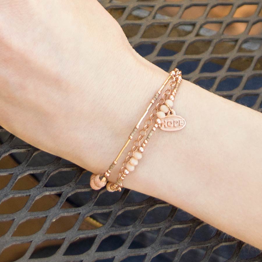 Woman wearing delicate rose gold beaded medical ID bracelet with cream and rose gold accents