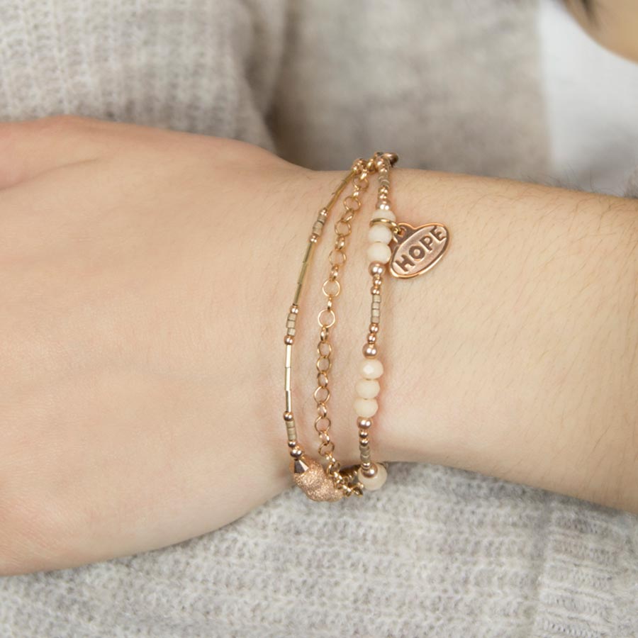 Woman wearing delicate rose gold beaded medical ID bracelet with cream and rose gold accents