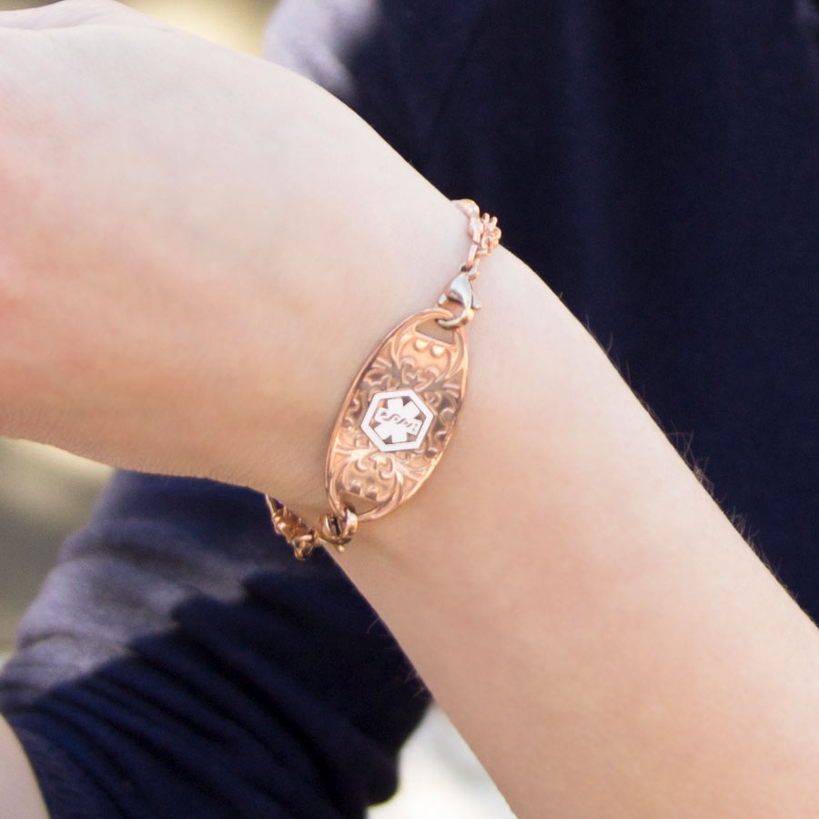 Woman showing decorative rose gold medical ID tag on beaded bracelet