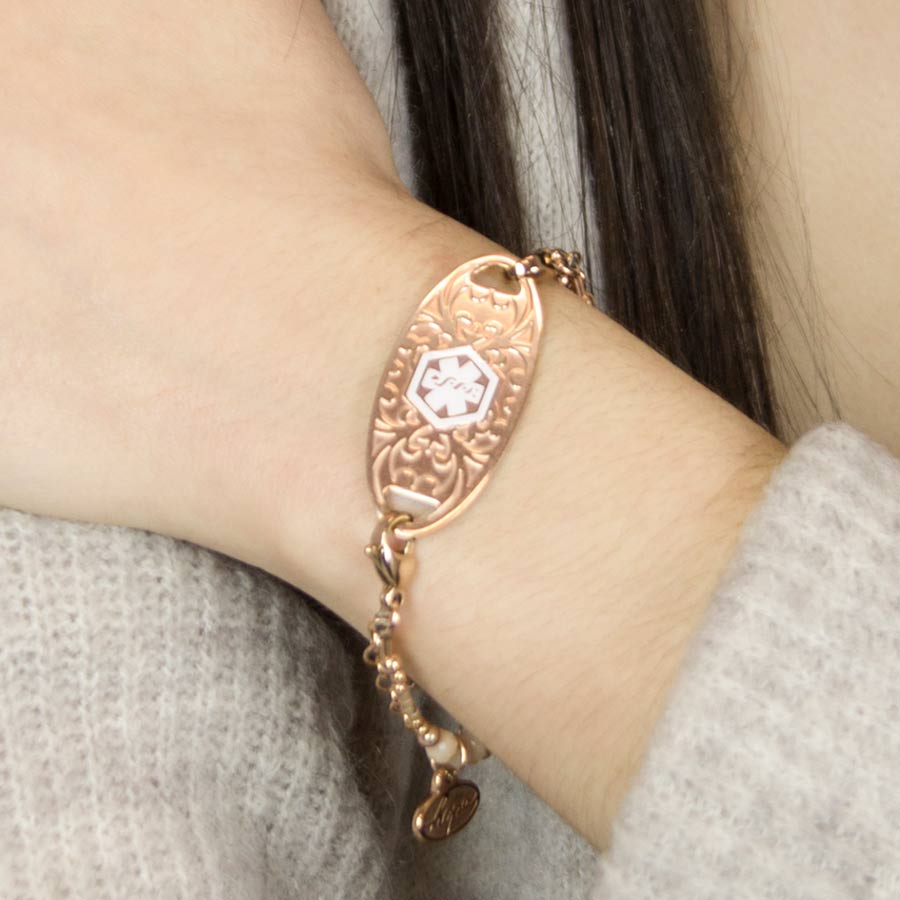 Woman showing decorative rose gold medical ID tag on beaded bracelet