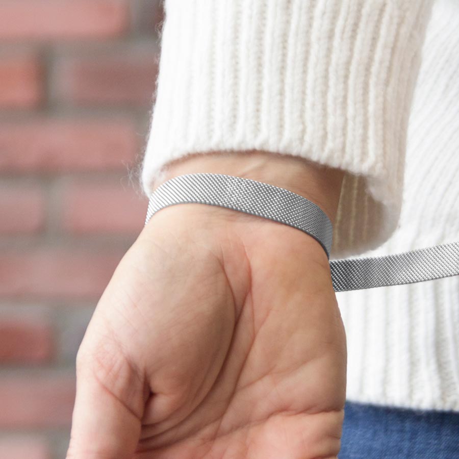 Woman showing the open mesh chain and slip-through magnetic closure on the silver-tone stainless Urban Medical Alert bracelet