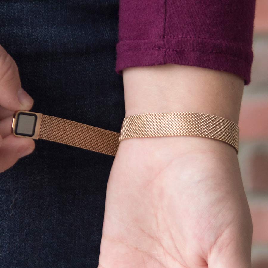 Woman showing the magnetic closure of Urban Medical Alert in Rose Tone with mesh chain and the affixed medical ID tag with white caduceus