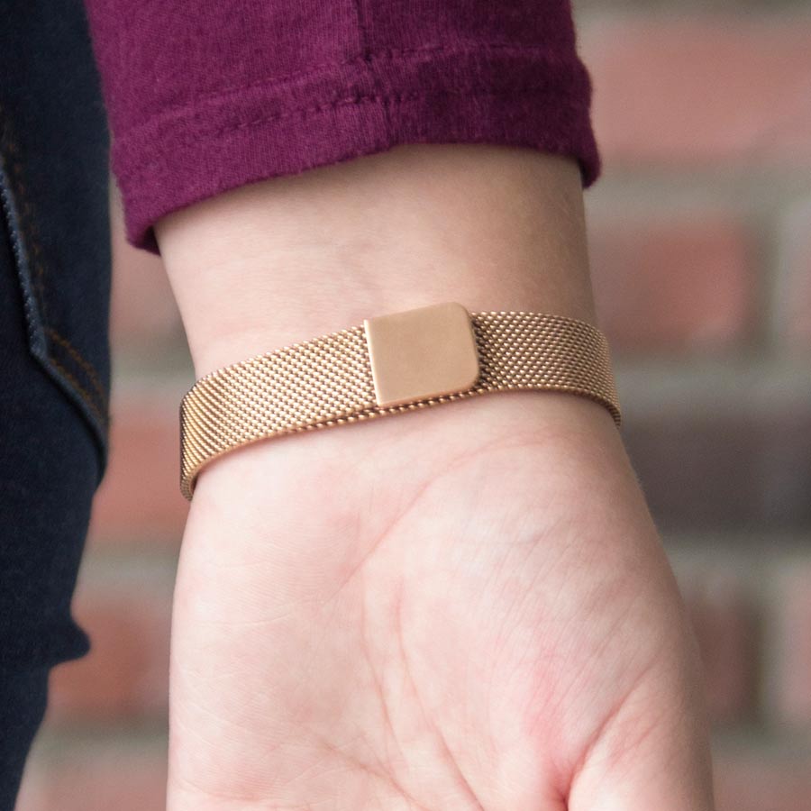 Woman showing the magnetic closure of Urban Medical Alert in Rose Tone with mesh chain and the affixed medical ID tag with white caduceus