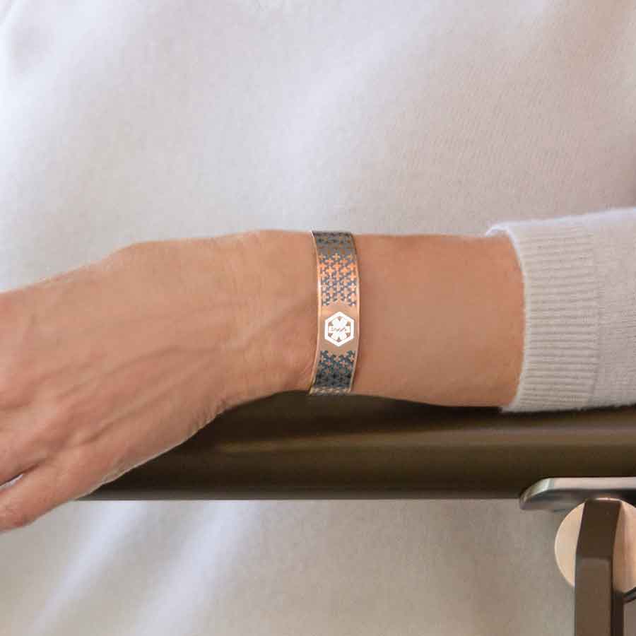 Woman wearing rose gold with blue decorative pattern medical alert cuff bracelet