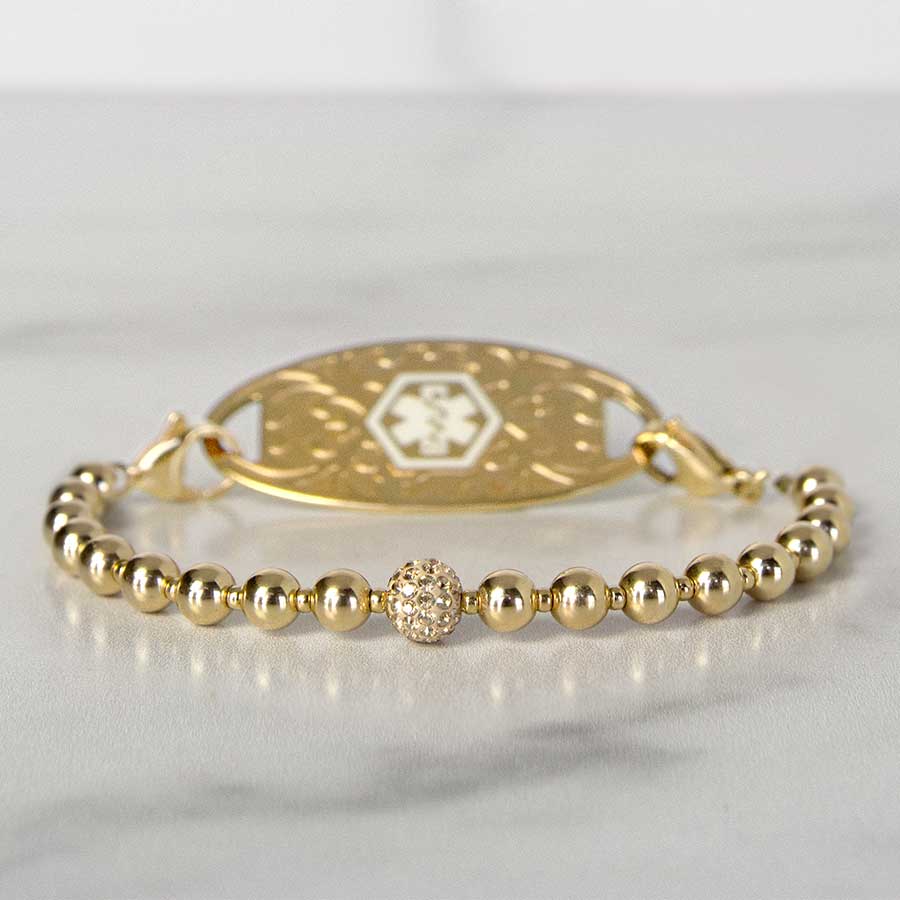 Gold tone beaded stretch medical ID bracelet on marble