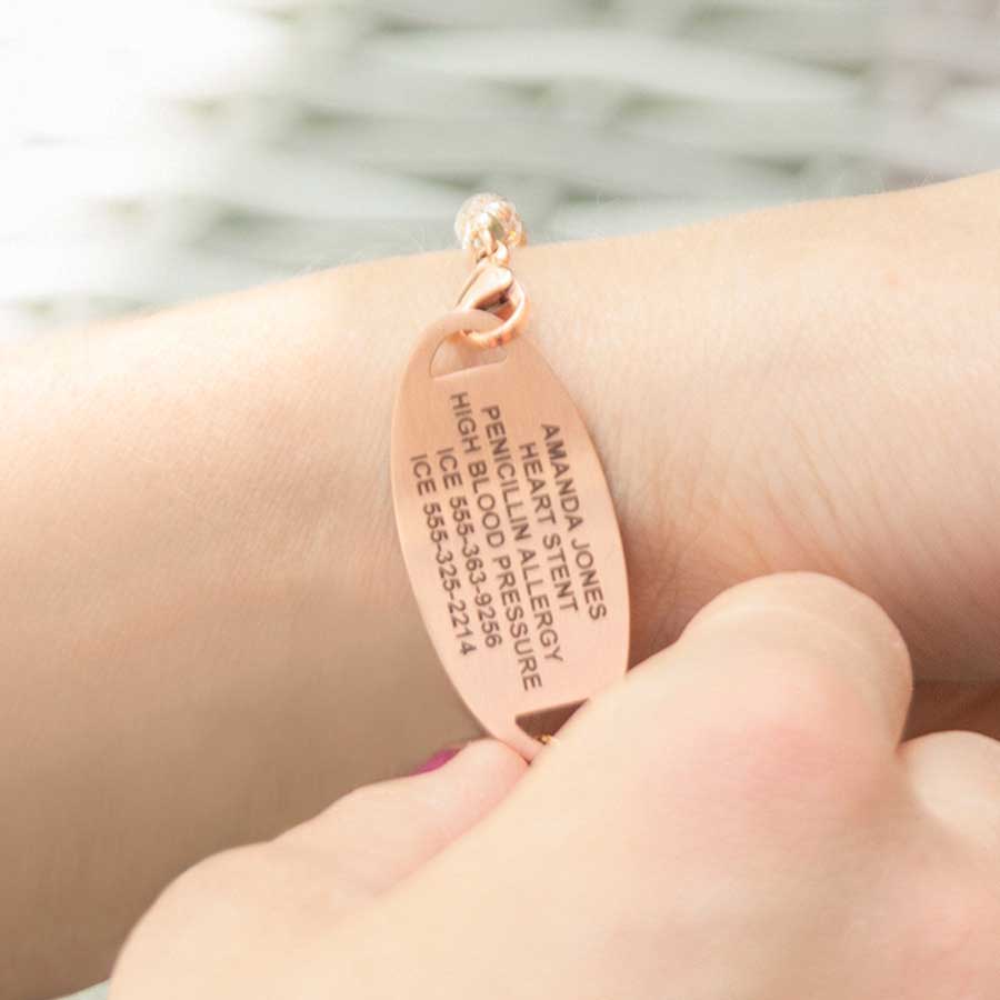 Woman showing custom laser engraving on a rose gold medical ID tag