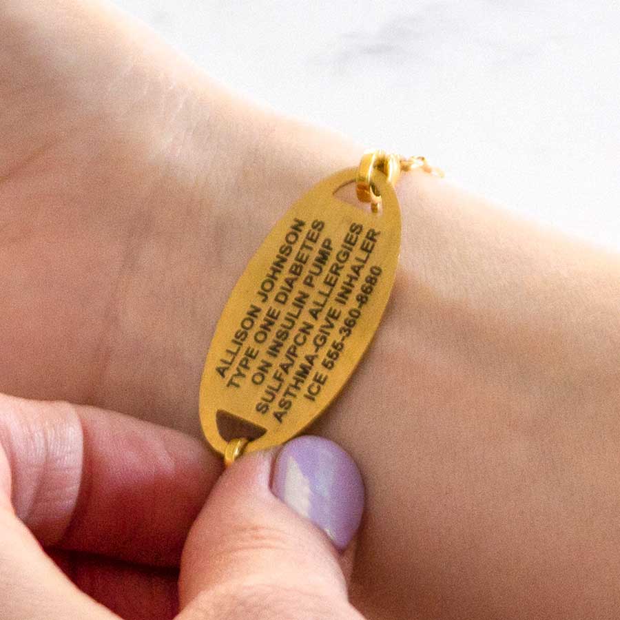 Woman showing custom engraved gold medical alert tag with laser engraving