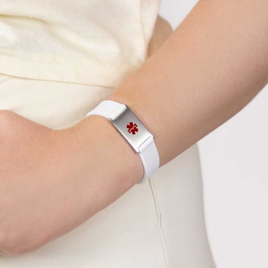 Woman wearing white silicone medical alert bracelet with stainless steel tag with red caduceus symbol