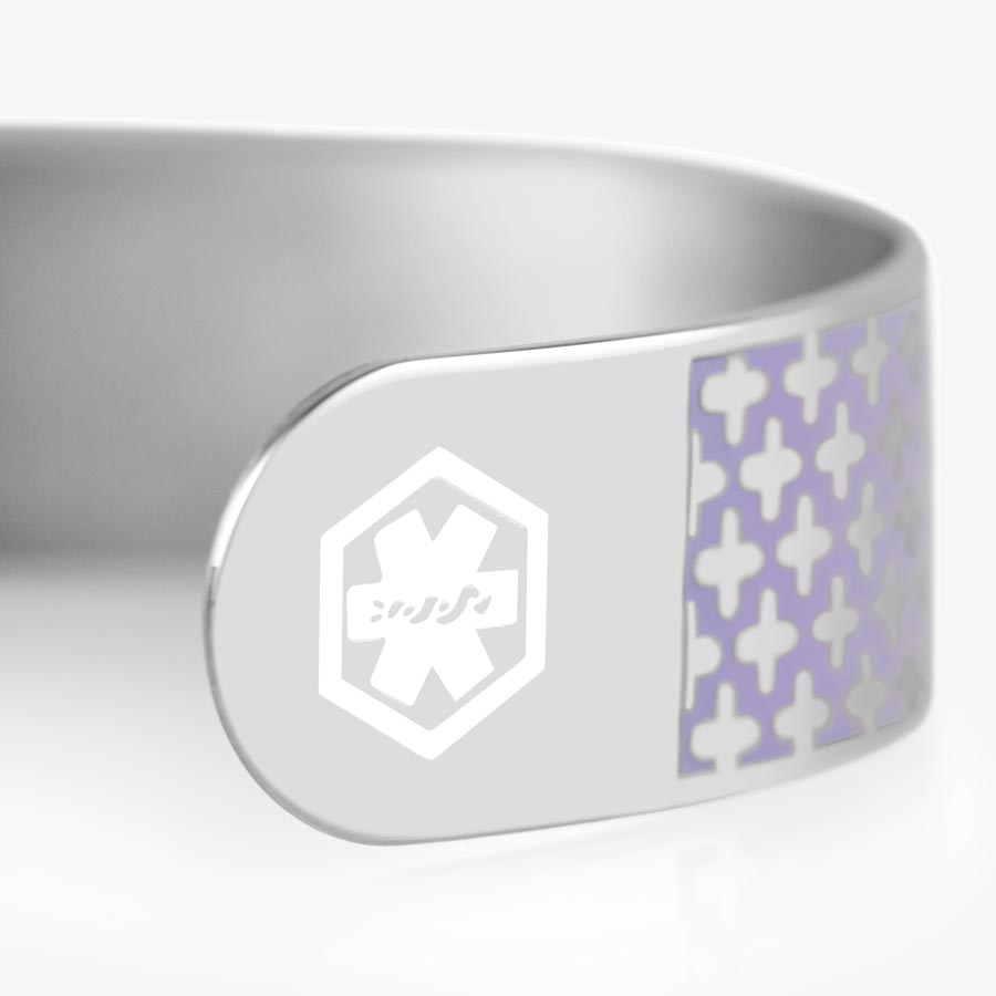 A close up view of silver tone medical ID cuff bracelet with lavender pattern and white medical symbol at the end of the cuff.