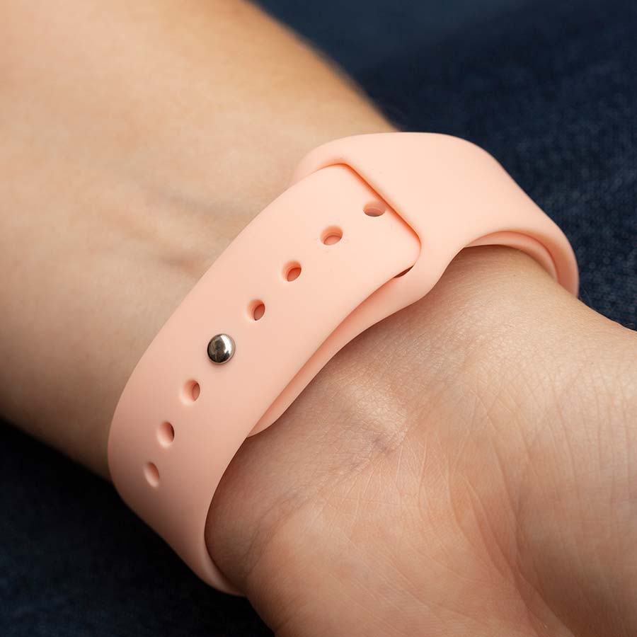 Close-up of pin-tuck watch band closure on pink silicone band on woman&#39;s wrist.