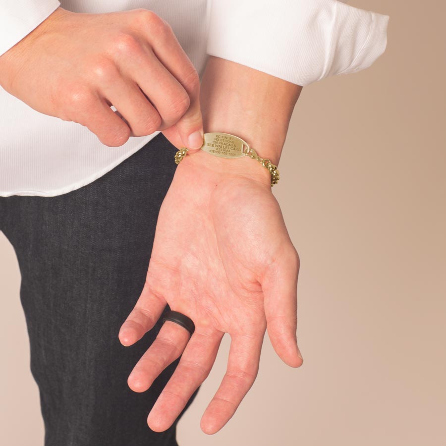 Man showing precision laser engraving on gold tone stainless steel medical ID tag.