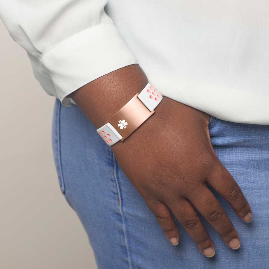 Woman wearing white and peach silicone medical ID alert bracelet with rose gold tag and white caduceus