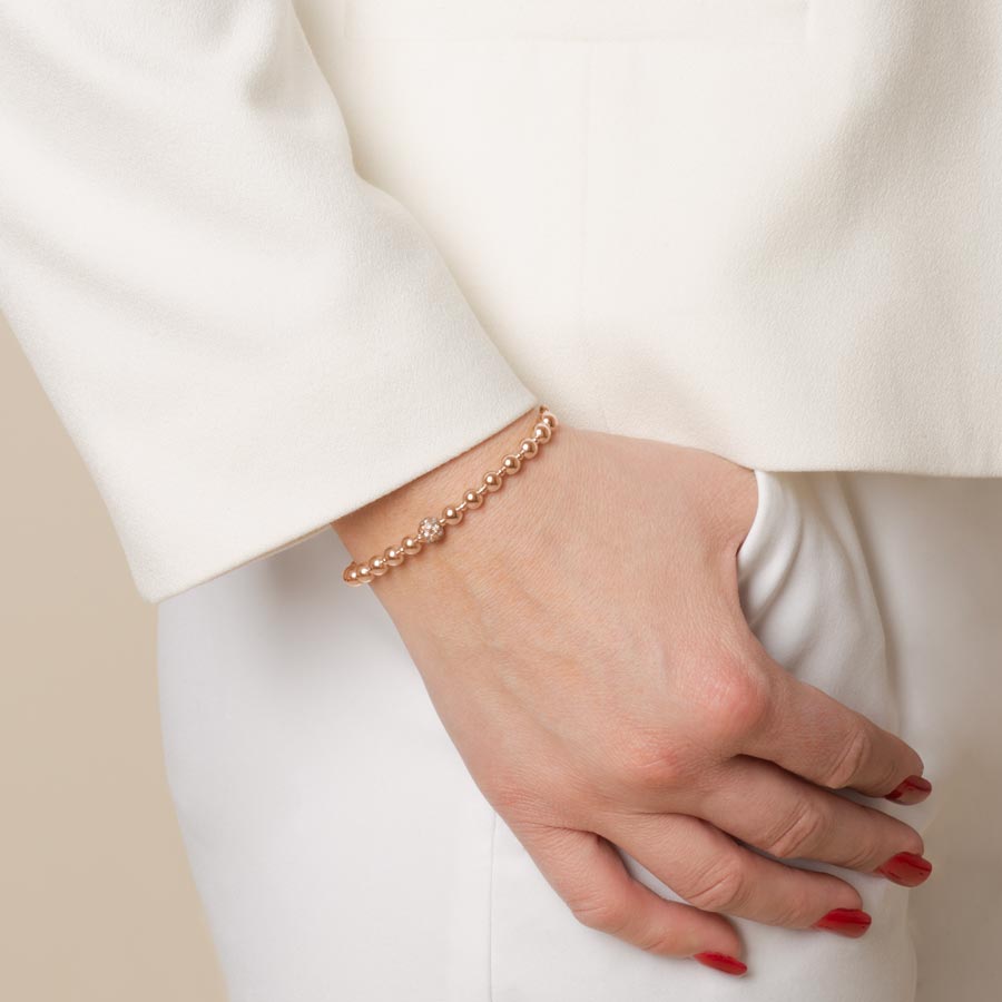 Woman with thumb in pocket wearing rose gold beaded medical ID bracelet