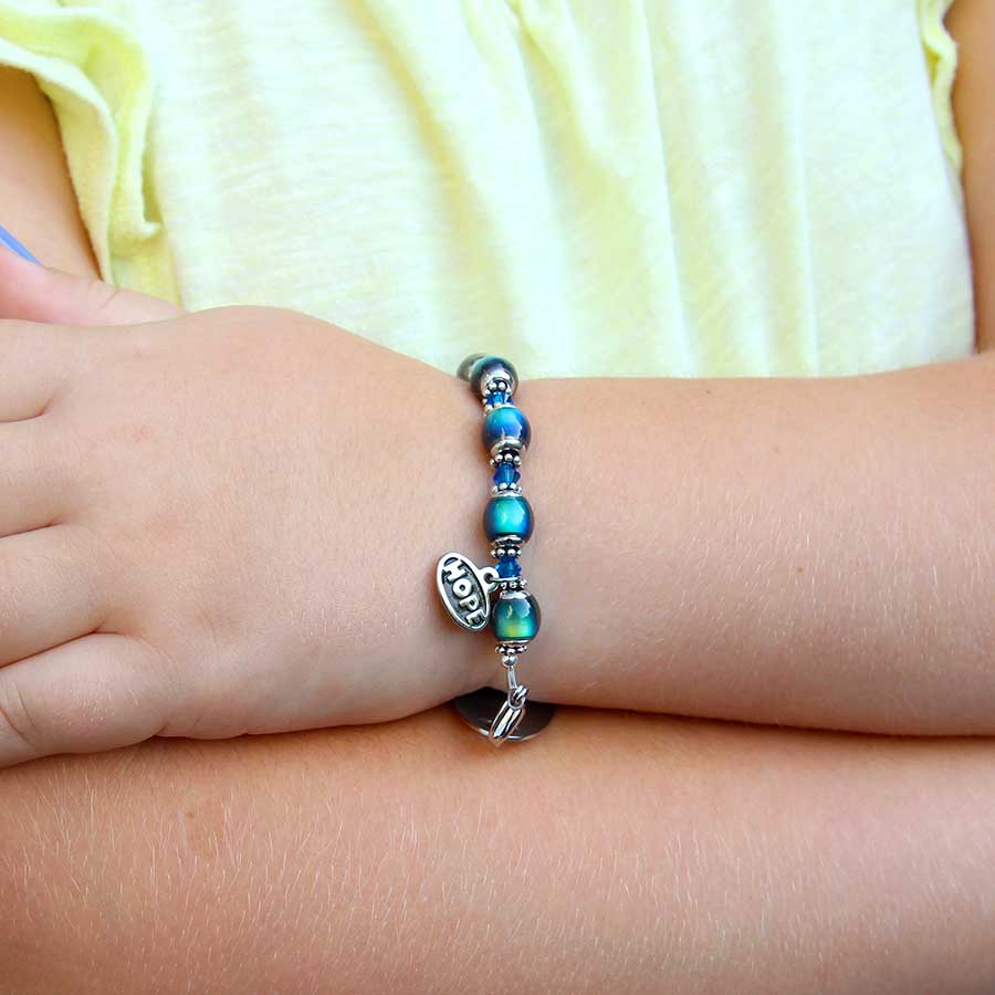 Young girl with arms crossed wearing fun mood bead medical ID bracelet