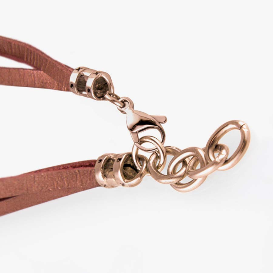 Brown leather bands attach to a rose gold medical ID tag. Fastens on wrist with a lobster claw clasp.