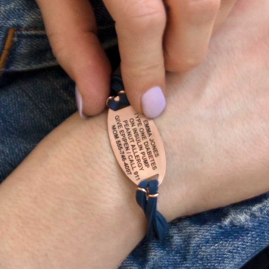 Woman showing custom laser engraved rose gold medical ID tag