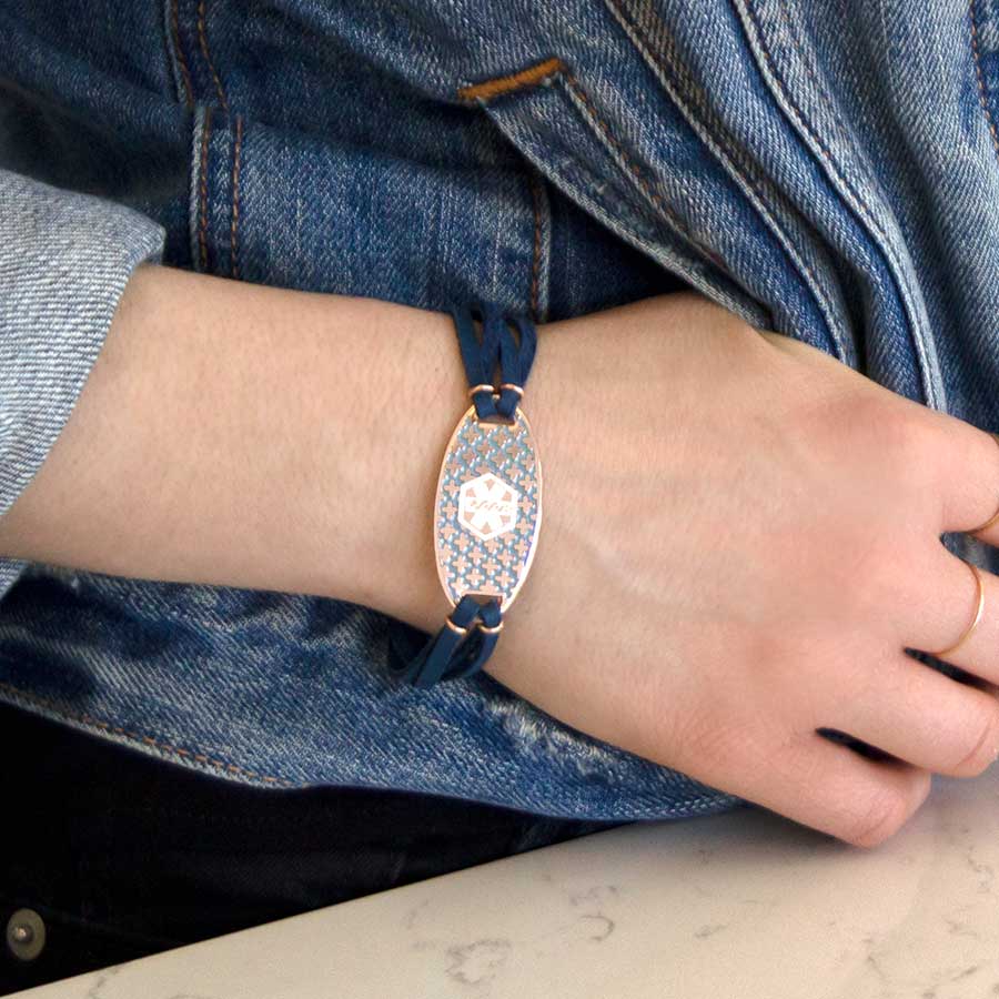 Woman wearing rose gold and navy blue medical ID bracelet with decorative medical ID tag